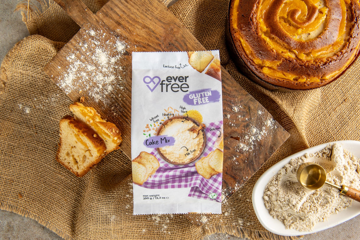 EverFree Gluten-Free Cake Mix bag on a wooden board with a baked cake, cake slices and a bowl of the dry mix