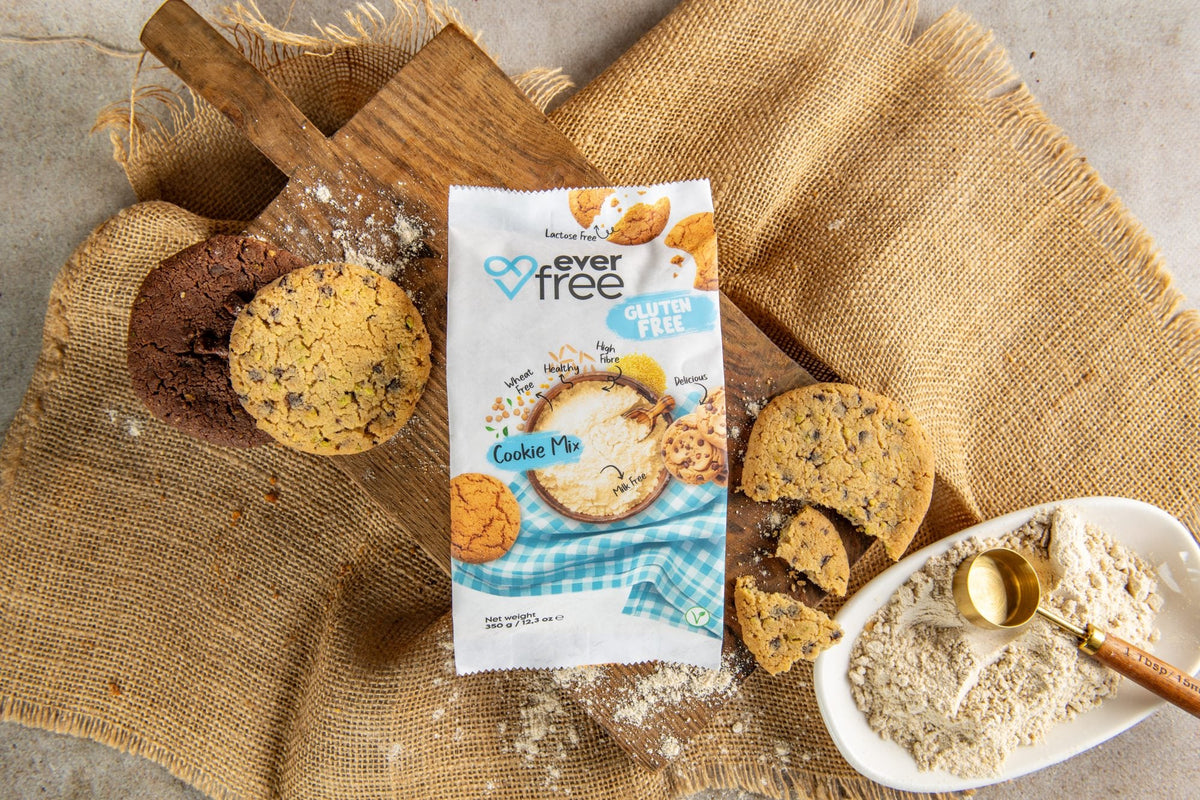 EverFree Gluten-Free Cookie Mix bag on a wooden board with baked chocolate chip cookies and a bowl of the dry mix