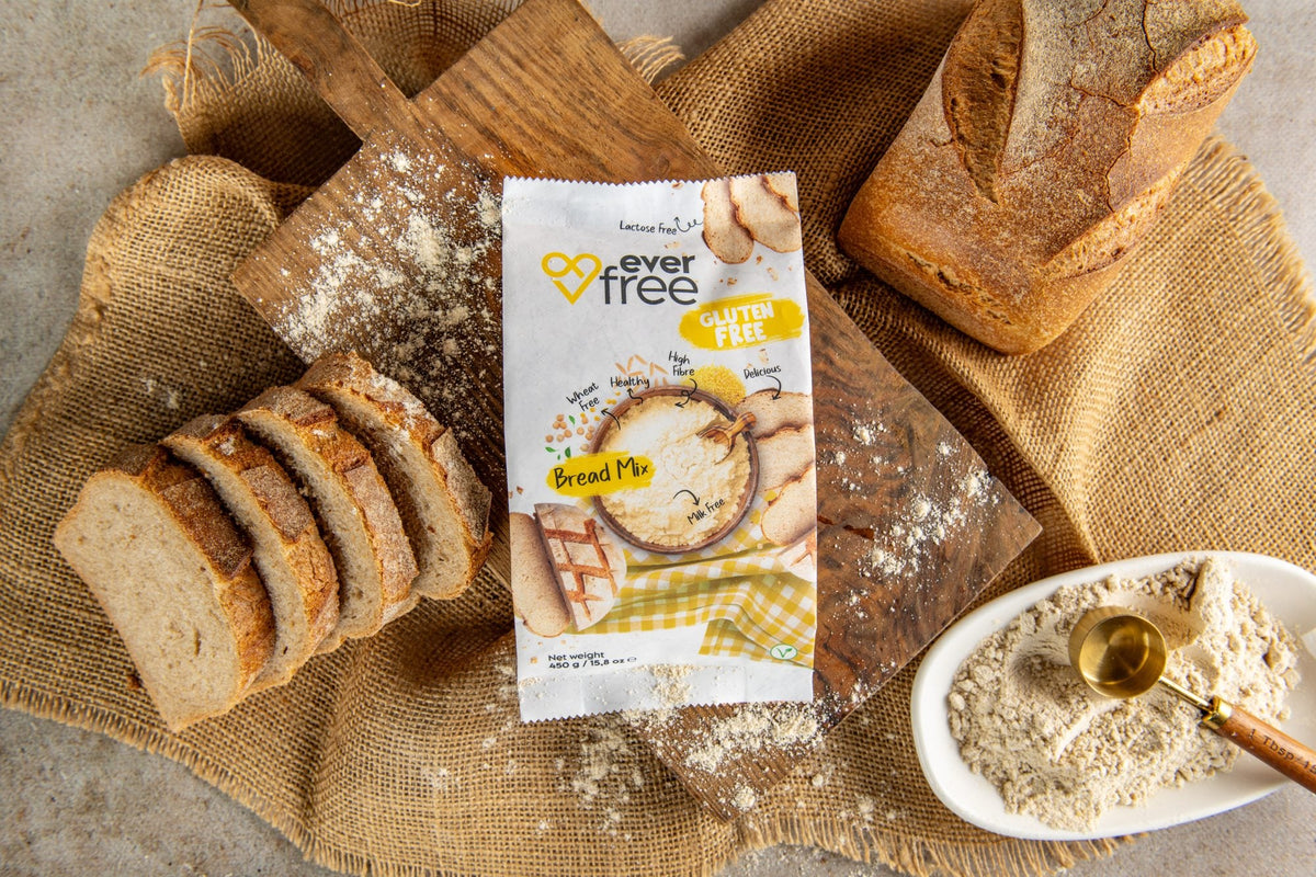 EverFree Gluten-Free Bread Mix bag on a wooden board with a sliced sourdough loaf and a bowl of the dry mix